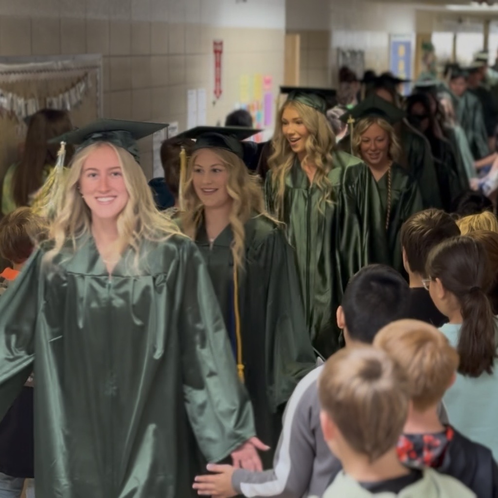 Graduates receiving high fives from elementary students.