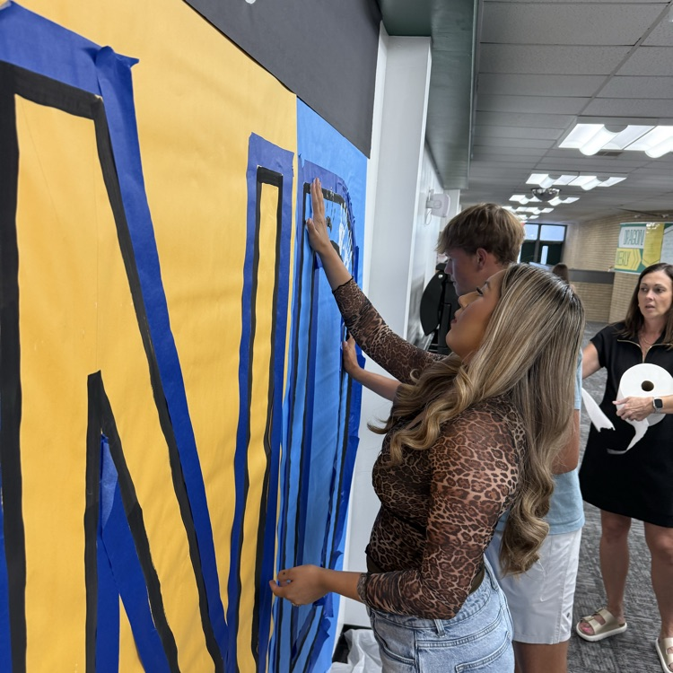 students paint their hand prints on paper taped to the wall