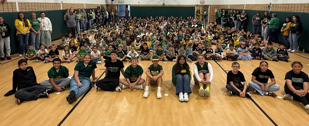 100s of kids sitting on the gym floor.