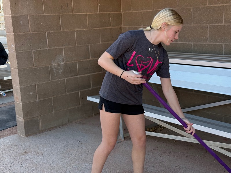 Student sweeping a baseball dugout