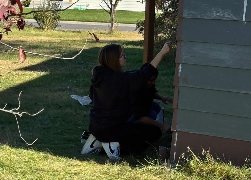 student works on painting a shed
