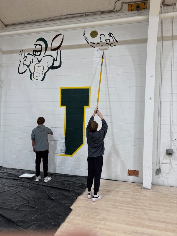 students painting a wall white to cover old paintings