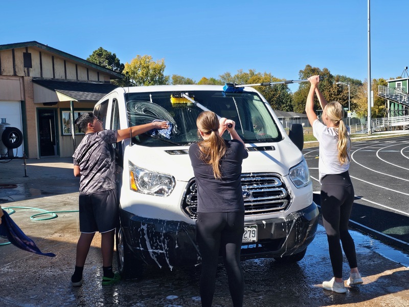 students washing the outside of a school van