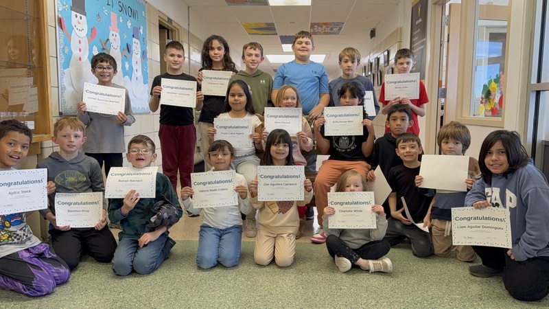 Students in a hallway holding certificates
