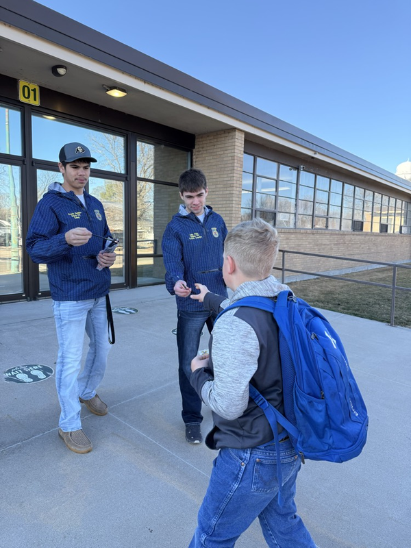 high school students greet elementary students in front of the school