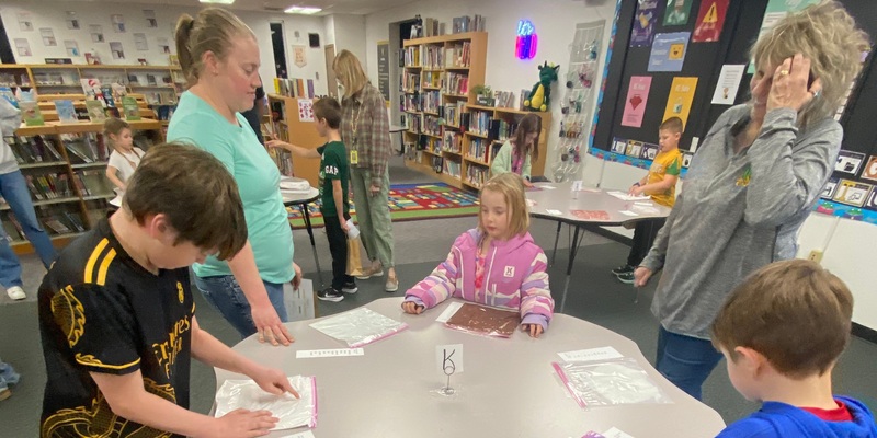 two adults flank a child in a pink coat at a table
