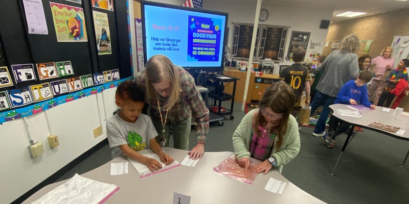 a teacher helps two students with a project