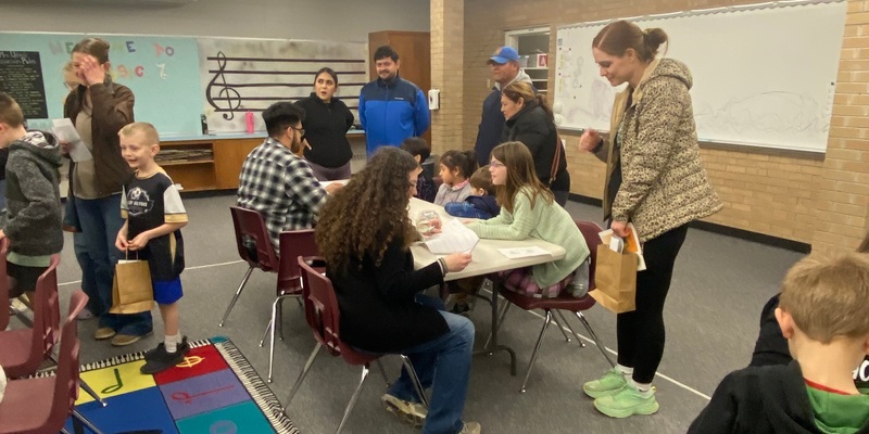 many people are gathered around a table eagerly participating in an activity.