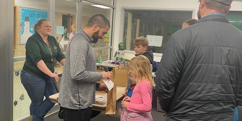 students look in gift bags while their teachers and parents look on and smile