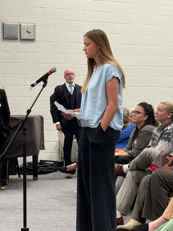 Student stands at a microphone and asks a question of supreme court visitors