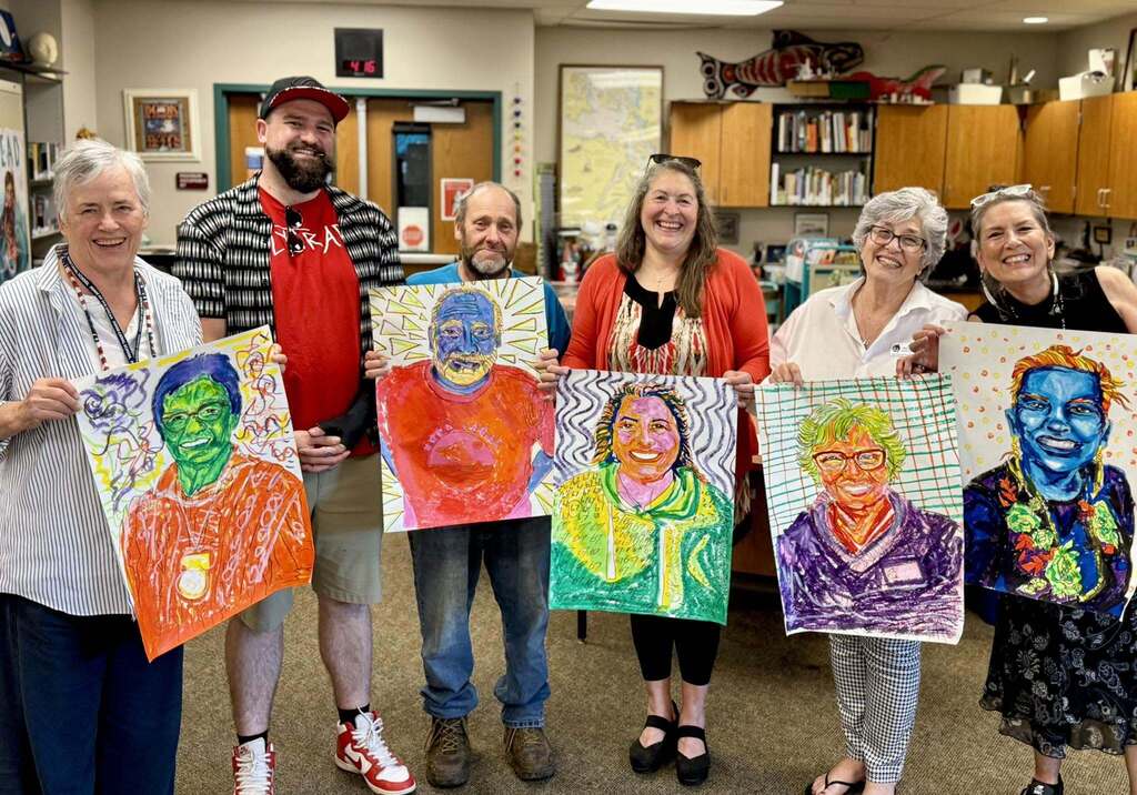 Mr. Max proudly displays the vibrant colorful portraits his talented students created for each school board member.