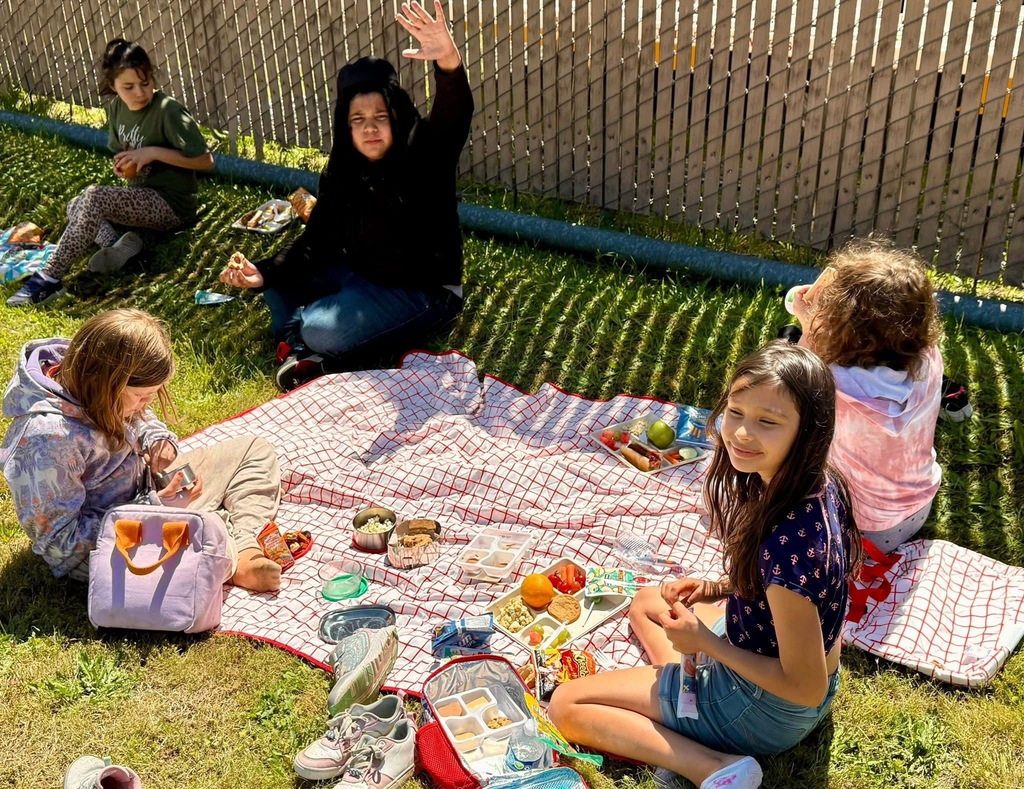 Students enjoying their lunch outside in the sun.