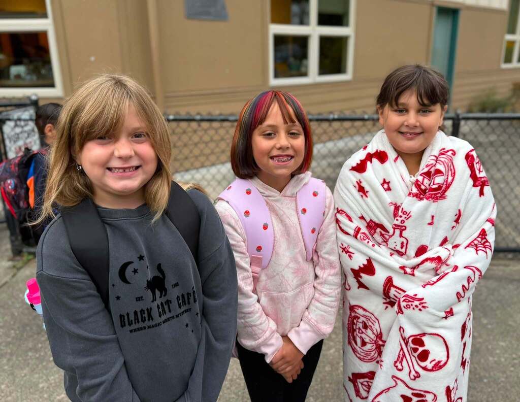 Three friends with big smiles ready to start the 1st day of school.