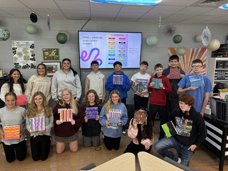 8th grade students holding canvases with words of the year painted on them  