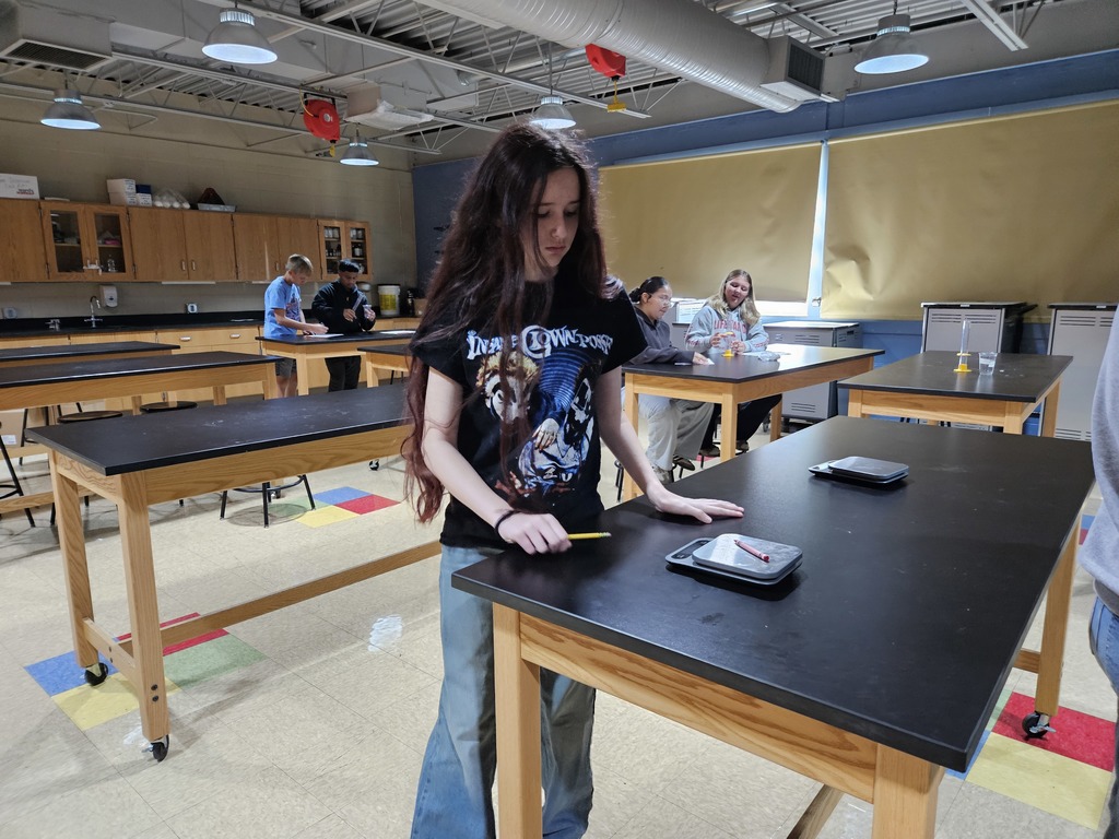A student places a crayon on a digital scale to determine the mass of the object.