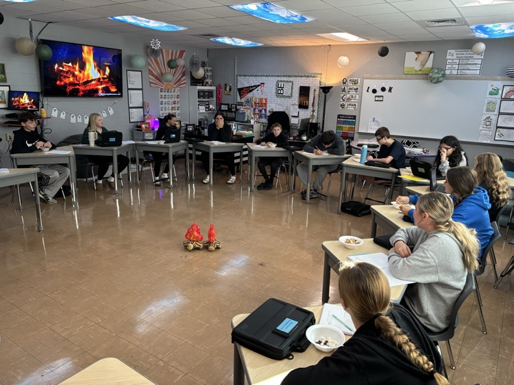 Students sitting in a circle around an inflatable campfire
