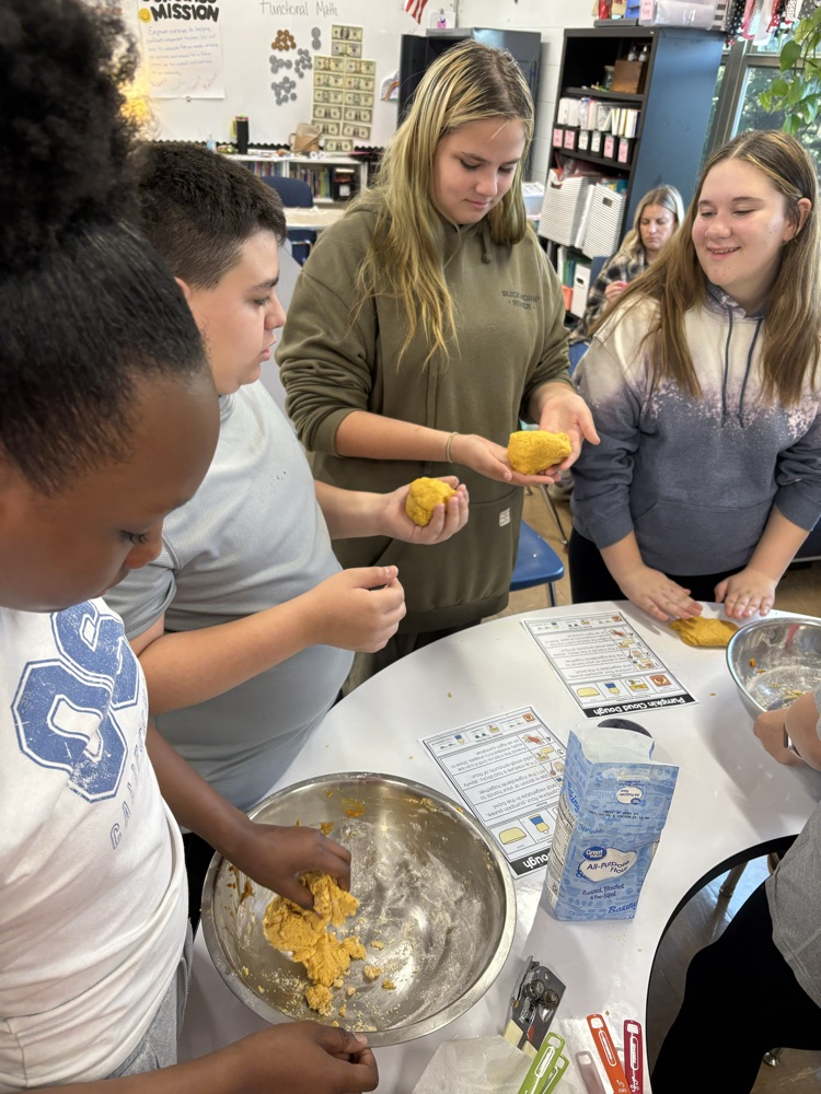 four students mixing cloud dough