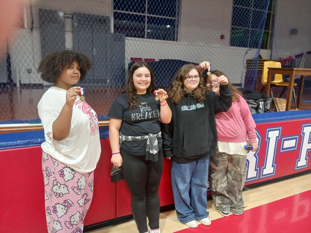 Four students holding up their first place medals after the performance.
