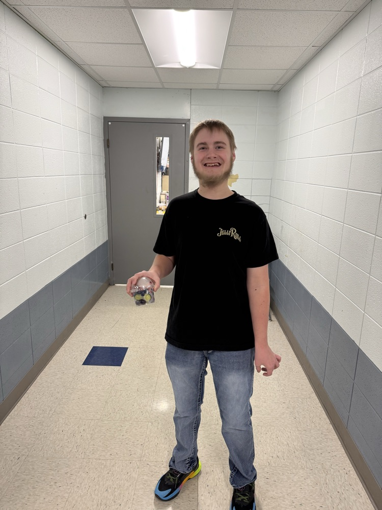 a male student holding a fruit cup in a school hallway 