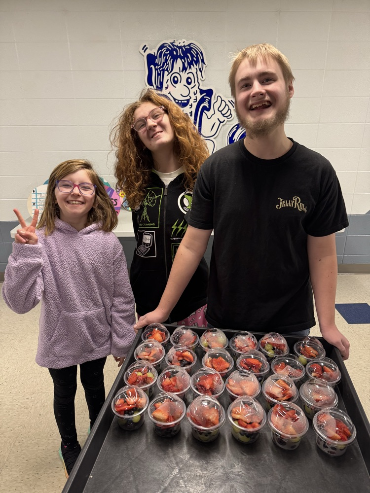 three students pushing a cart holding fruit cups 