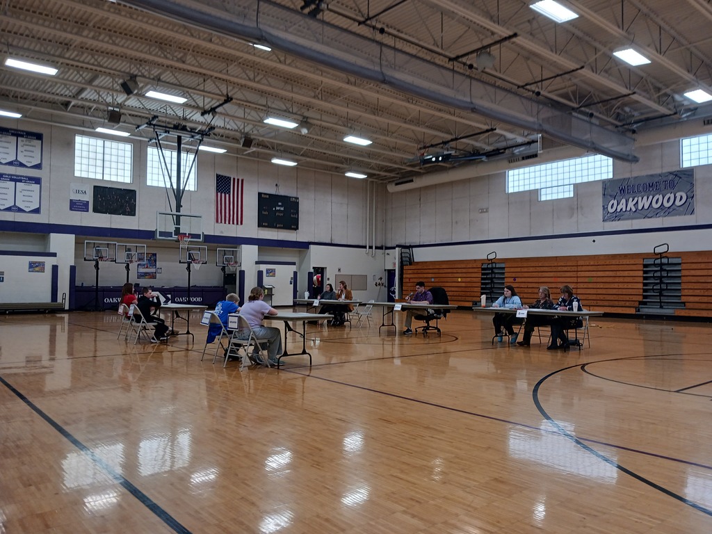 Student participants in the sectional spelling contest facing judges and officials in the Oakwood gymnasium.