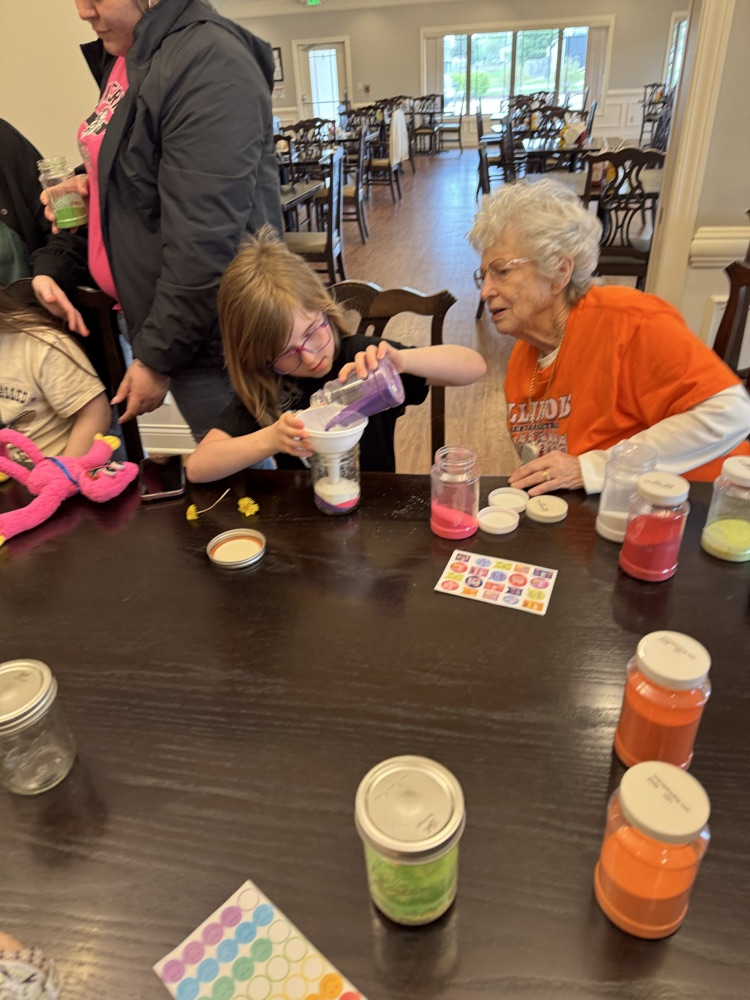 student pouring purple sand 