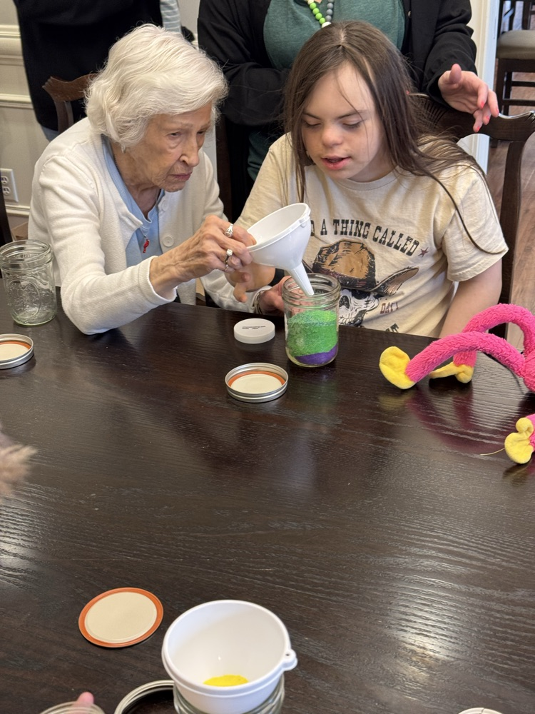 student working with pal to make craft 