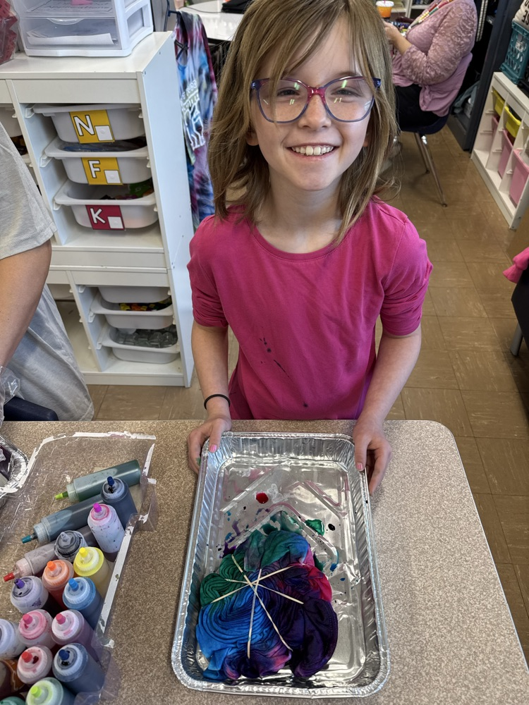 a small student tie dying a shirt 