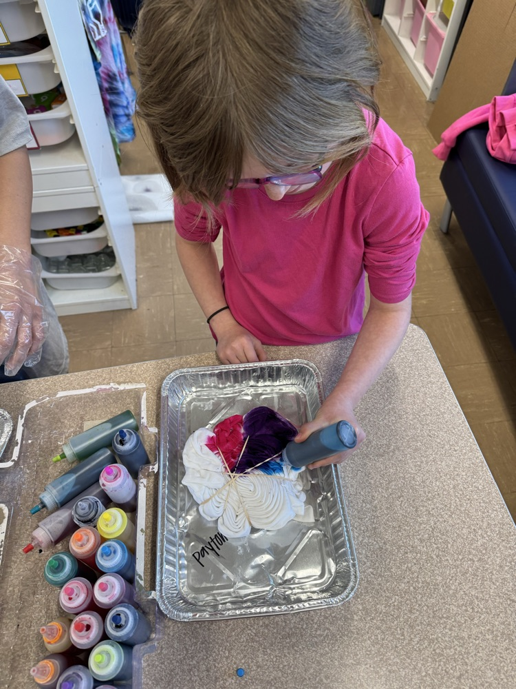 a small student tie dying a shirt 