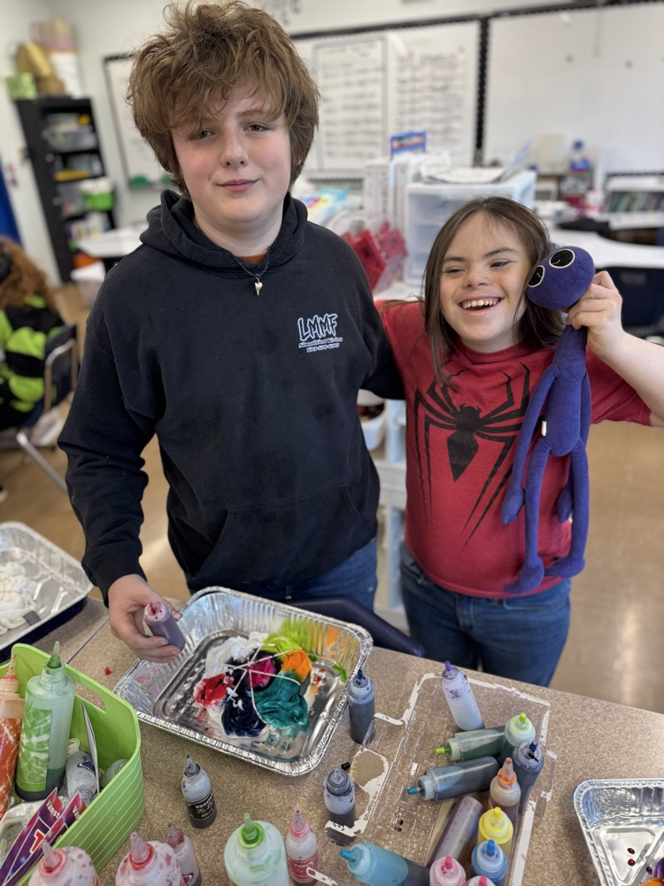 two students working on tie dye together while smiling 