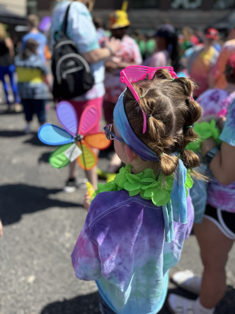 a student standing with a colorful flower with her hair in braids 