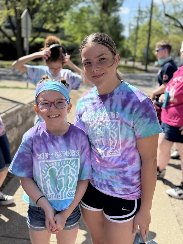 two middle school girls smiling with purple tie dye shirts 