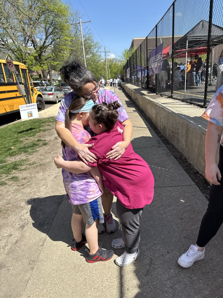 students hugging a teacher outside 
