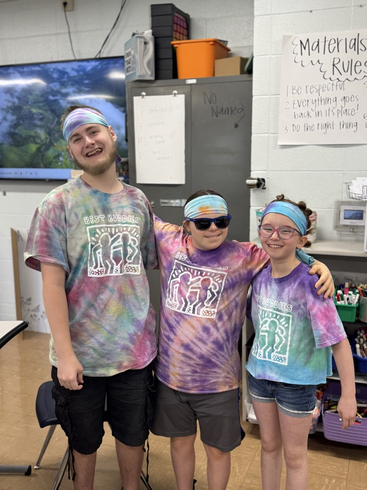 three students posing together in their tie dye shirts 