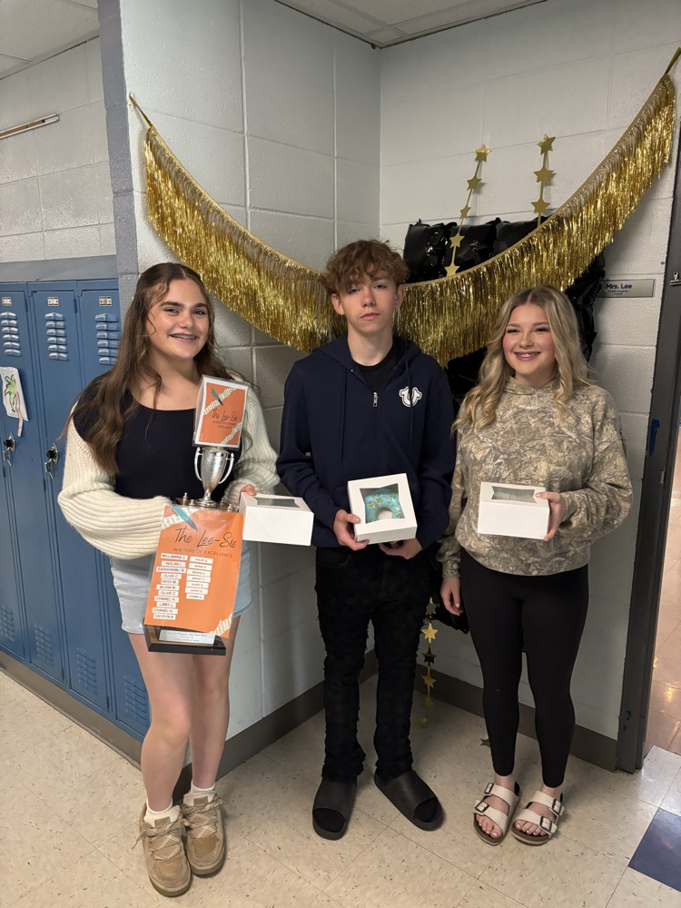 Girl holding trophy, with two other students holding their prizes for the contest  