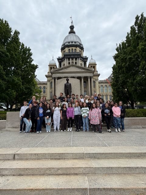 Students standing on the steps of the Illinois State Capitol in front of a statue of Abraham Lincoln 
