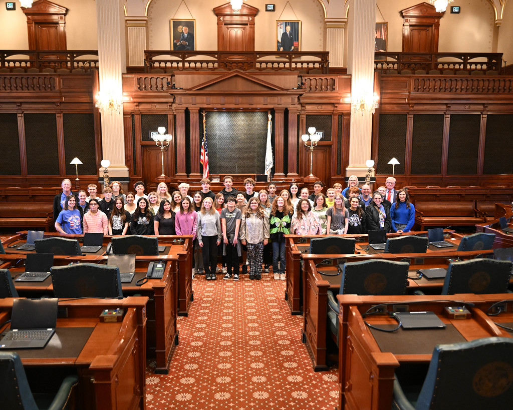 Students standing on the floor of the Illinois House of Representatives with Rep. Chris Miller