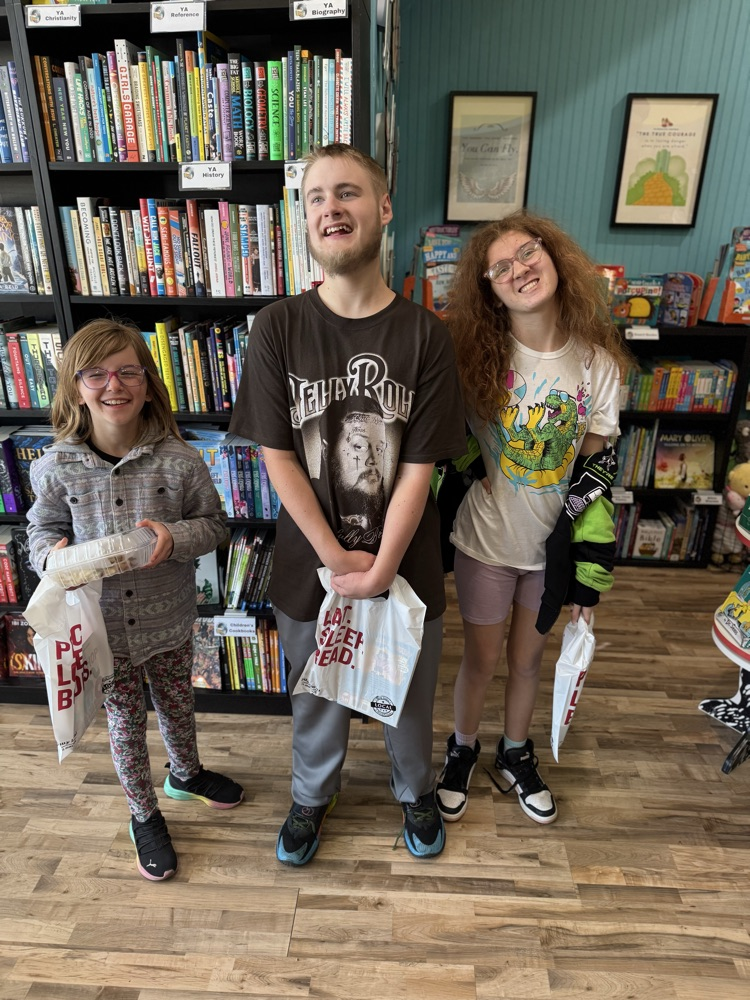 three students with books inside bookstore 