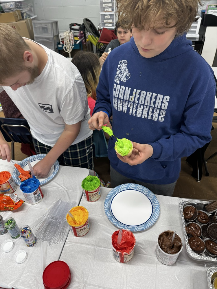 two students icing cupcakes 