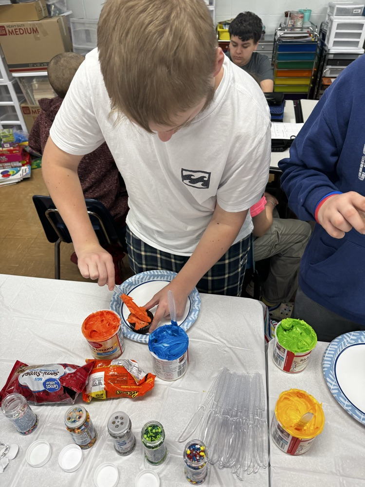 one male student icing cupcakes 