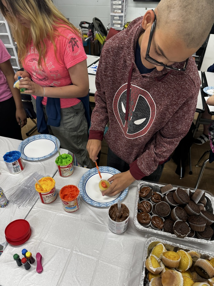 two students icing cupcakes