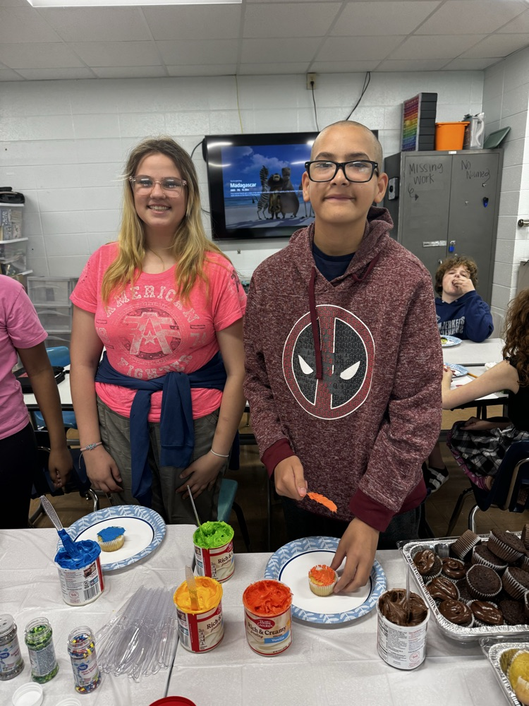 two students smiling with cupcake icing