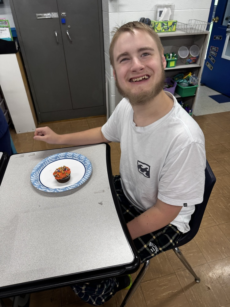 a student smiling with a cupcake