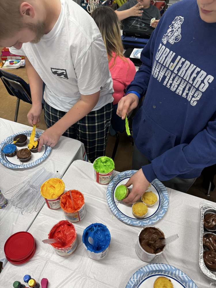 two students icing cupcakes 