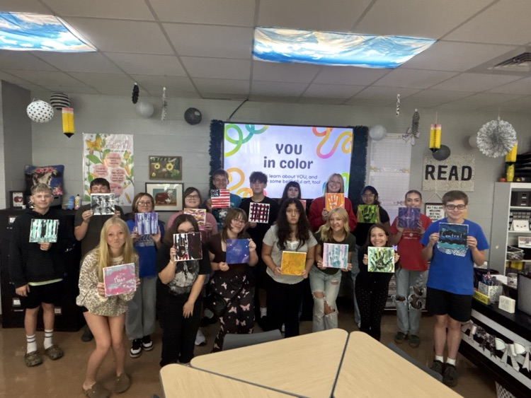 students pose with painted canvases