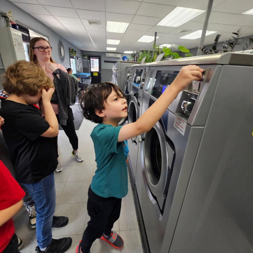 Elementary teacher Mrs. Cross has another “community integration field trip” to share! These trips allow students to explore some of the community helper roles they have been learning about in the classroom. Students visited the laundry mat in the Village! The kiddos made change, put coins into the washer, poured detergent, and watched the laundry spin! They walked to the store and purchased a drink, and then returned when the wash was done and put the blankets into the dryer. They did a great job, and they had an awesome time out in the community! Thanks for sharing, Mrs. Cross! 