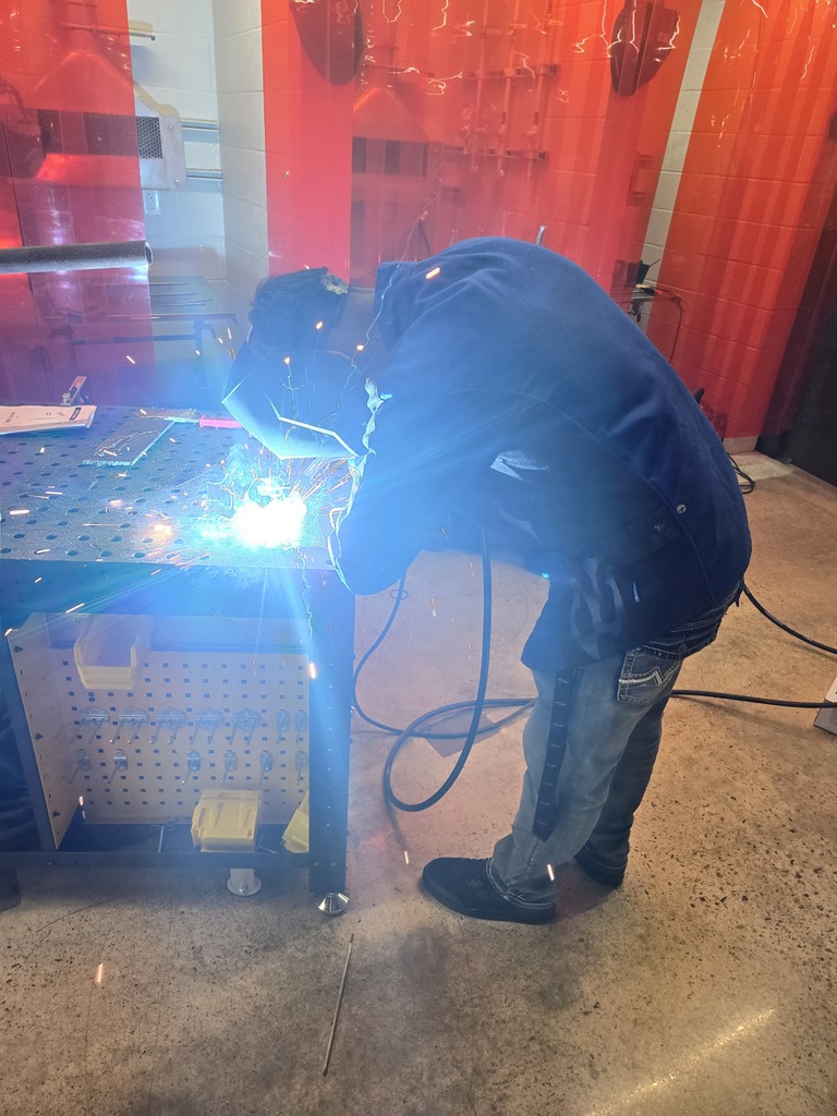 Hope High School agriculture students wearing welding helmets and protective gear practice MIG welding using new welding equipment in the Ag Department workspace.