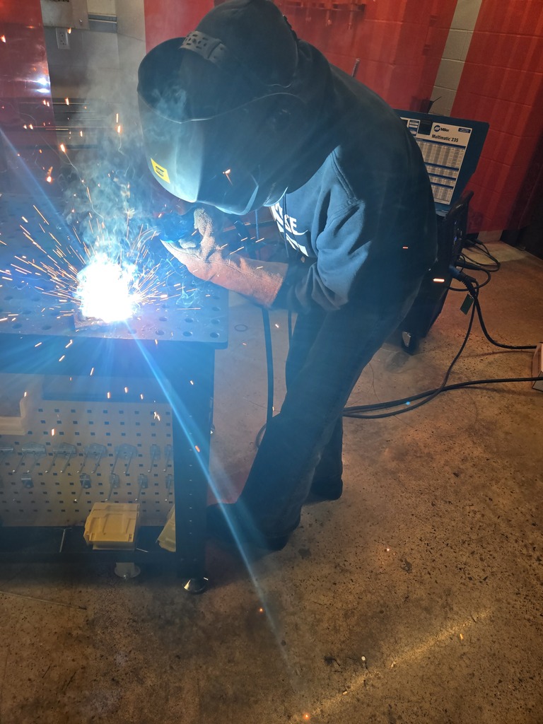 Hope High School agriculture students wearing welding helmets and protective gear practice MIG welding using new welding equipment in the Ag Department workspace.