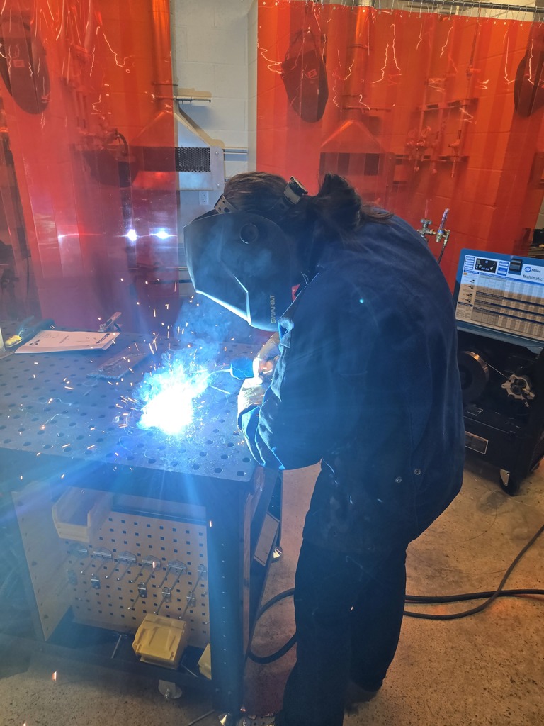 Hope High School agriculture students wearing welding helmets and protective gear practice MIG welding using new welding equipment in the Ag Department workspace.