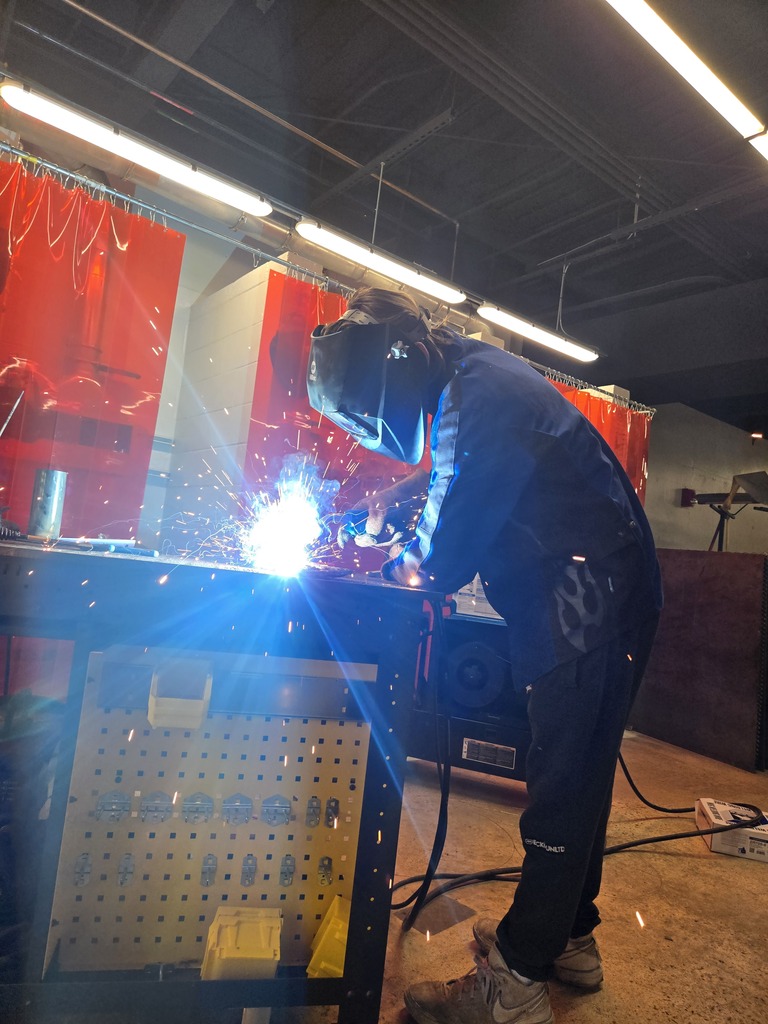 Hope High School agriculture students wearing welding helmets and protective gear practice MIG welding using new welding equipment in the Ag Department workspace.